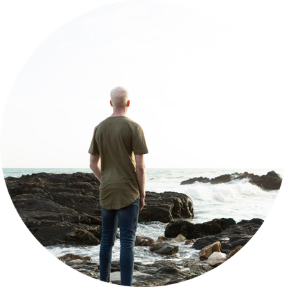 Un homme regarde au loin devant des roches sur le bord de l'océan
