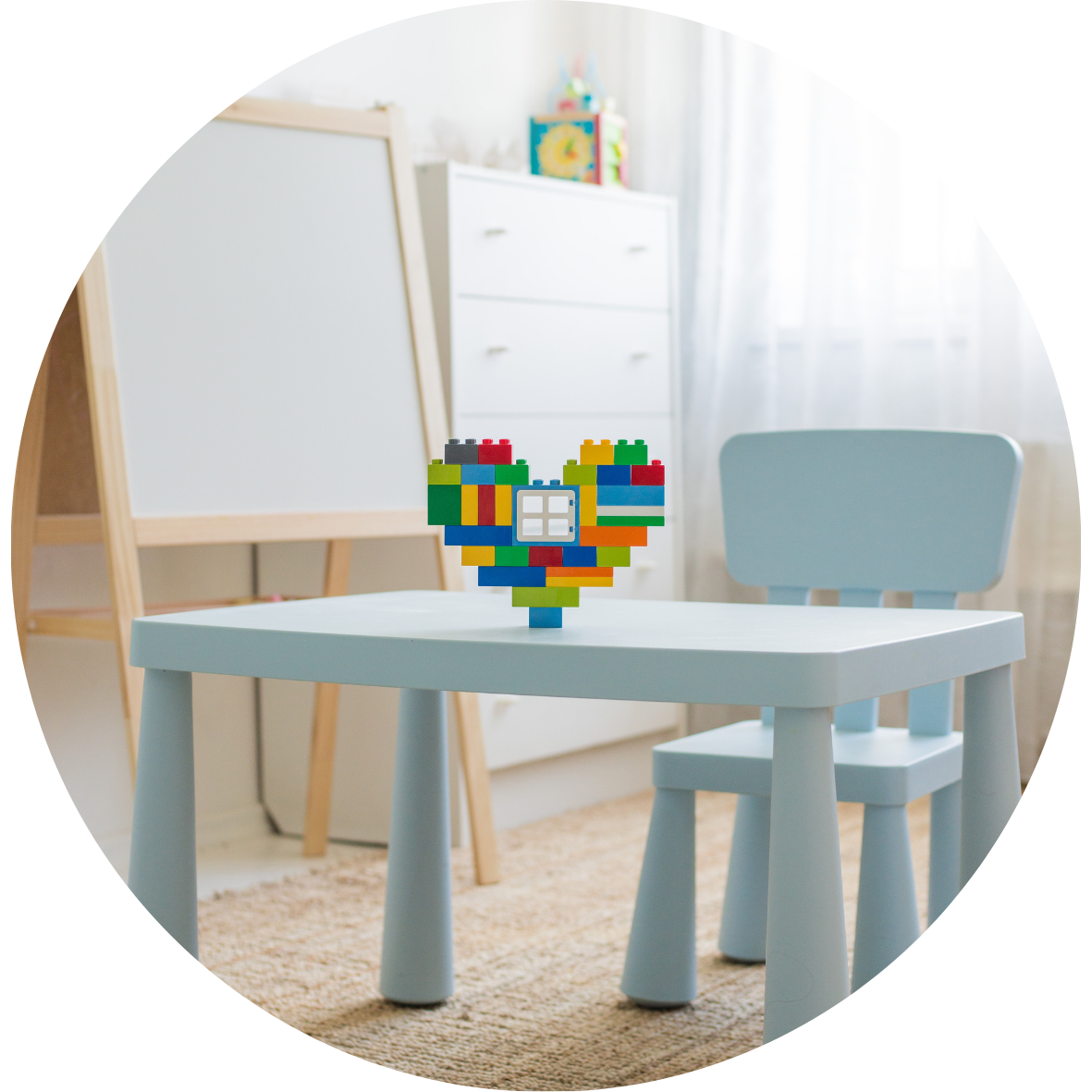 Petite table et chaise d’enfant dans un espace lumineux, avec un cœur coloré en blocs de construction posé au centre.